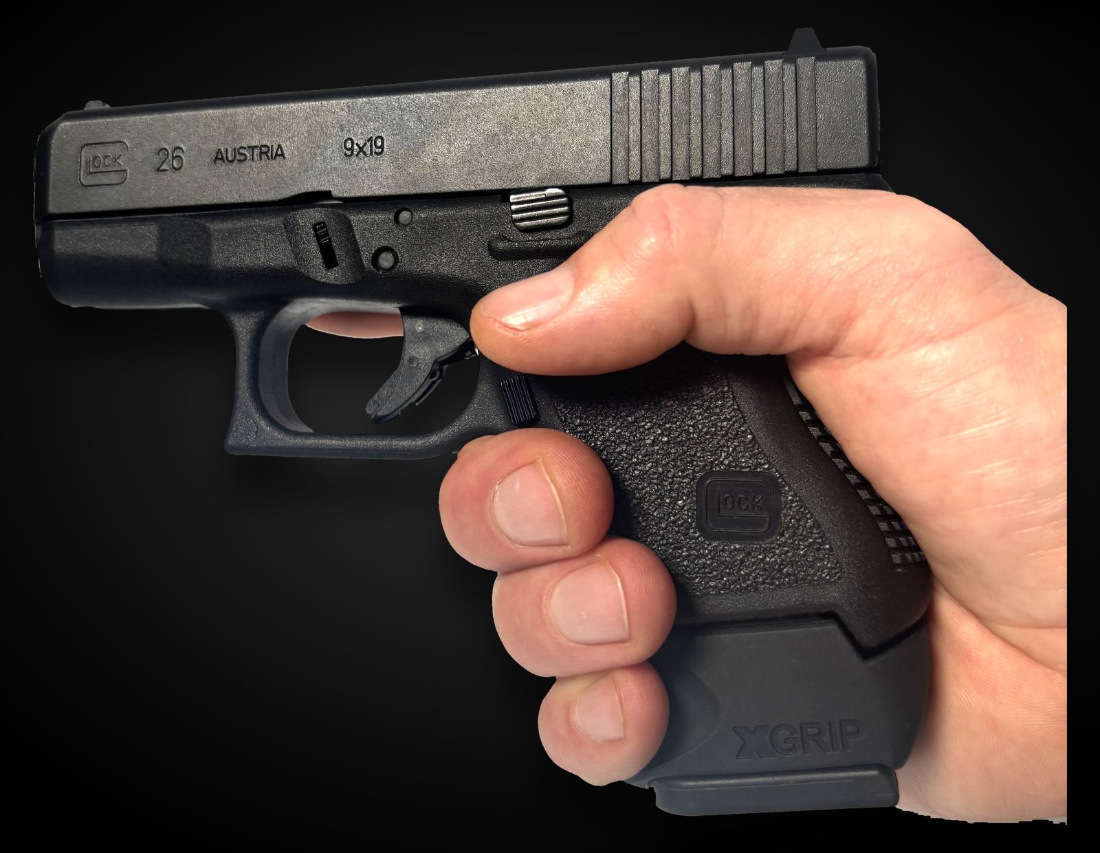 A GLOCK 26 with an XGRIP XGGL26-27C adapter fitted to a full-size magazine, held in the hand